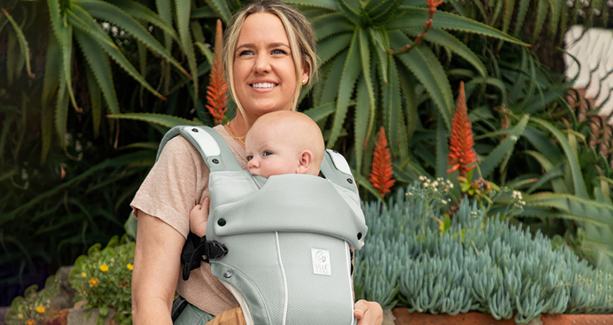 mom wearing baby in elevate air carrier in sea breeze